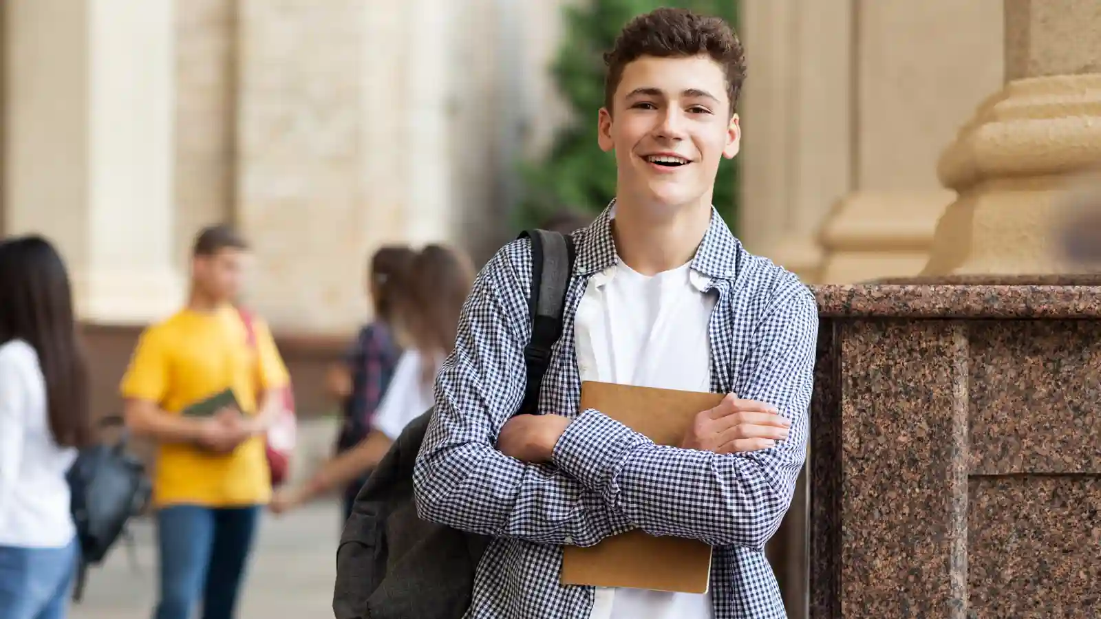 student standing with school bag and notes