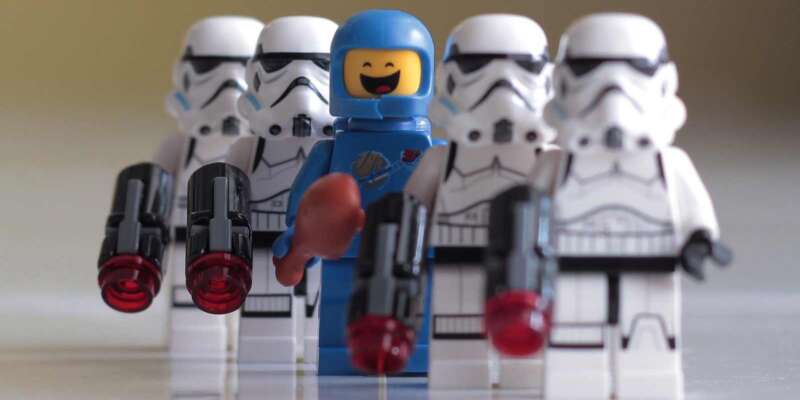 lego spaceman standing beside stormtroopers