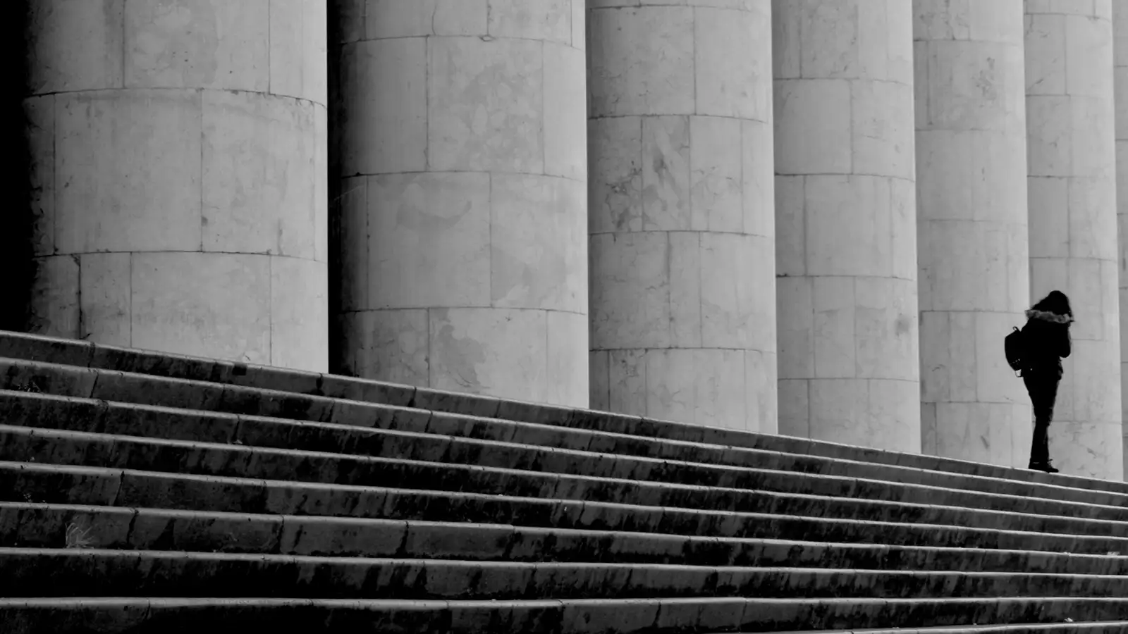 woman walking in front of columns