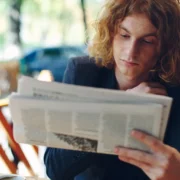 young man reading the Guardian newspaper